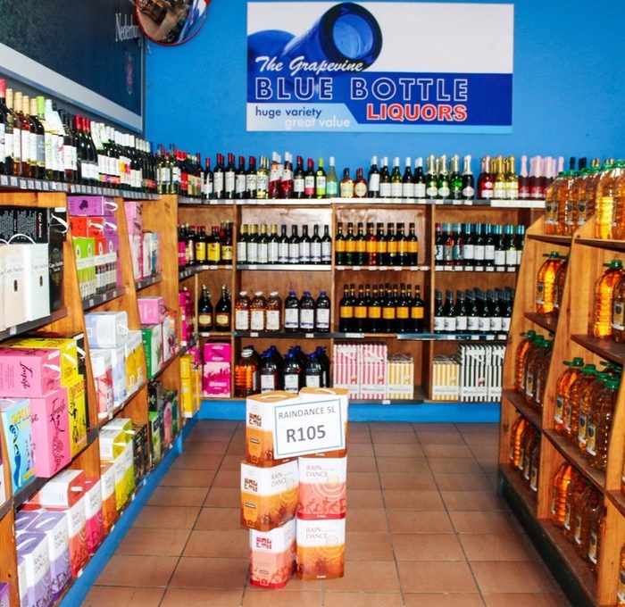 Interior of The Grapevine Blue Bottle Liquors showing stocked shelves of bottles and Blue Bottle Liquors signage.